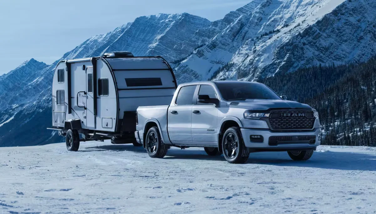 2026 RAM 1500 towing a camper through a snowy mountain landscape
